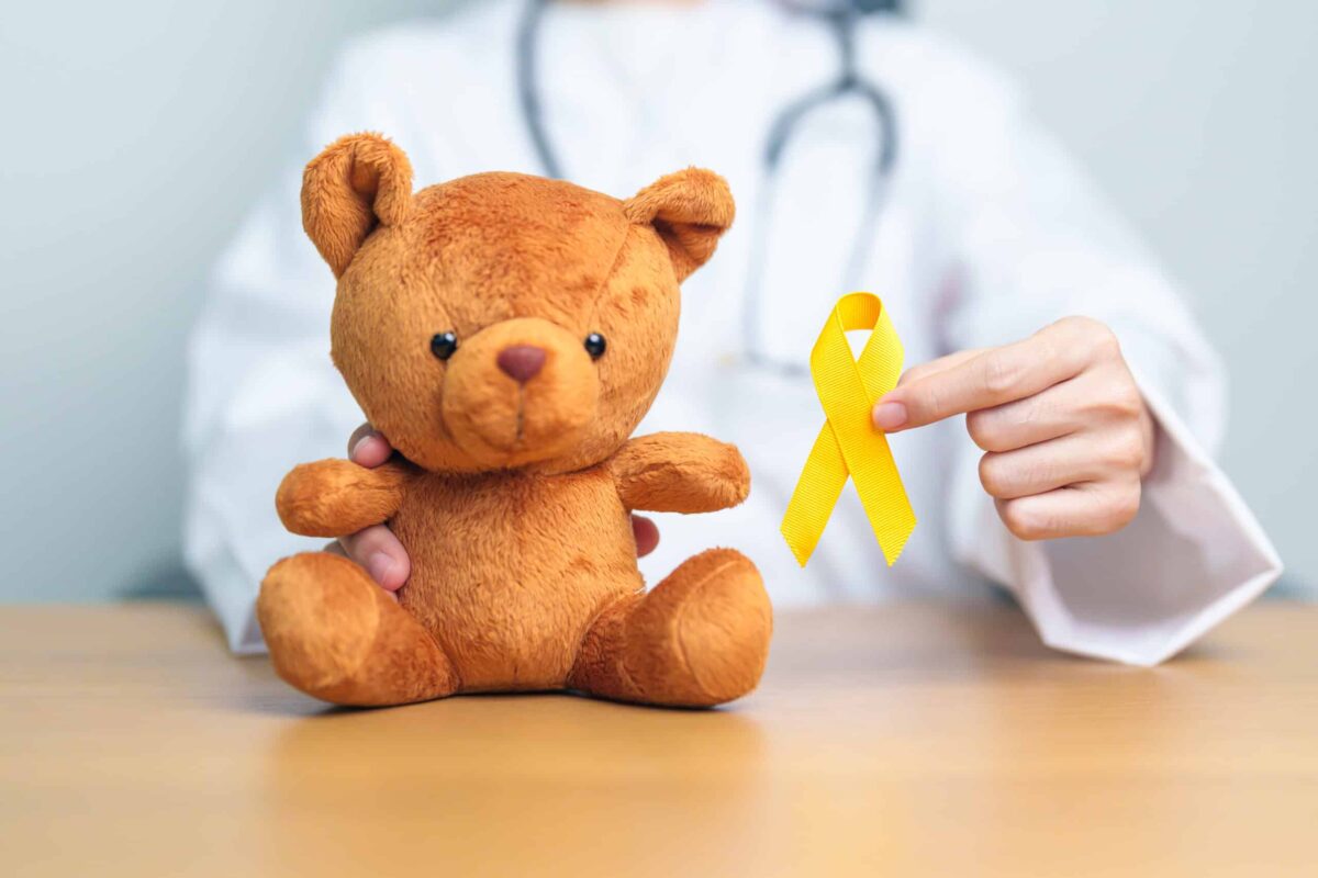 International Childhood Cancer Awareness month, Doctor with Children toy and golden color Ribbon for supporting kids living. Healthcare and World cancer day concept