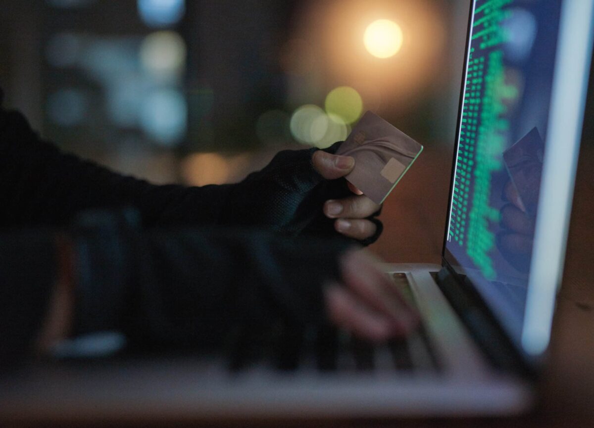 Shot of an unrecognisable hacker using a laptop to hack into a credit account.