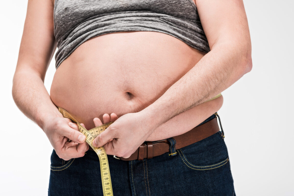 cropped view of overweight man measuring waistline with tape isolated on white