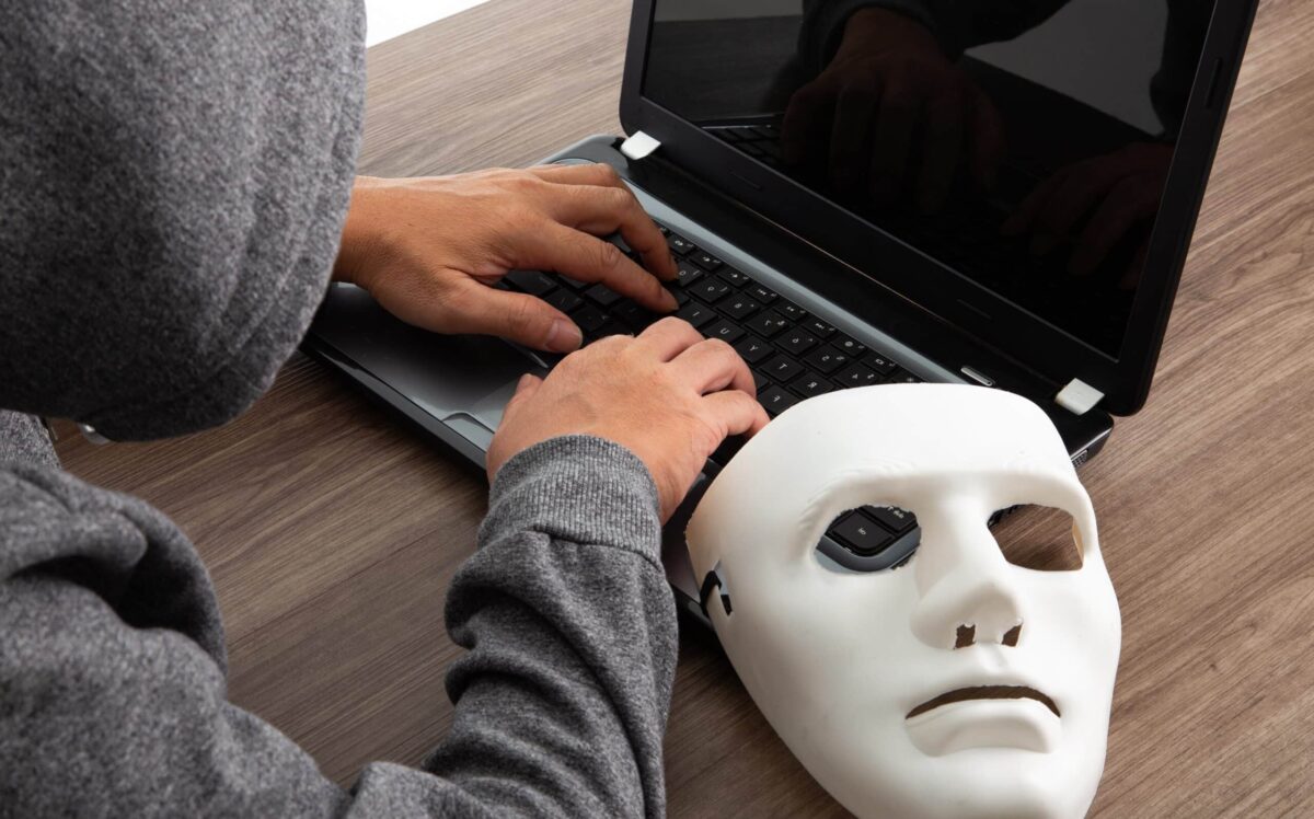 Thief hacker in mask stealing personal information from laptop. Concept hacking.