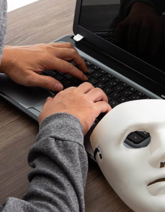 Thief hacker in mask stealing personal information from laptop. Concept hacking.