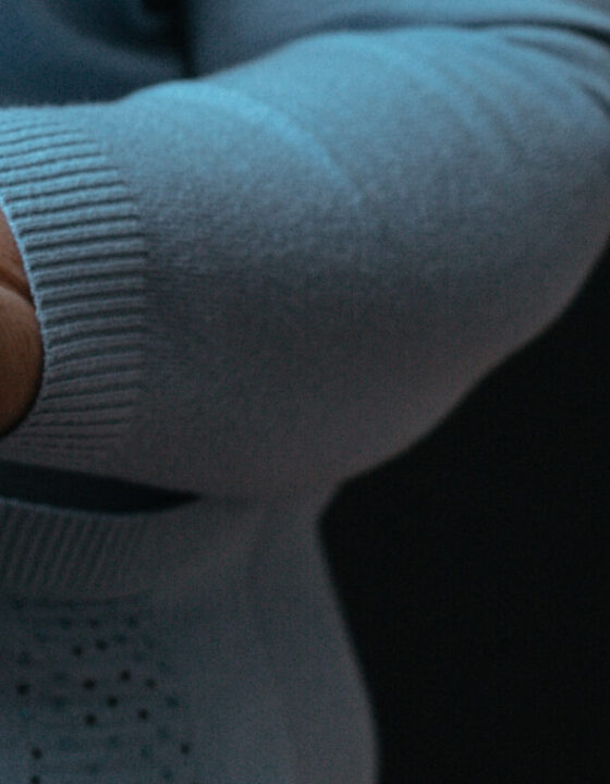 Old wrinkled woman's hands holding walking stick with dark background